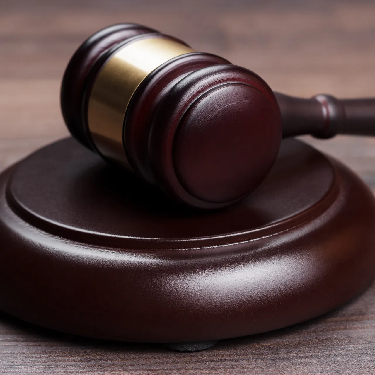 Martillo de juez de madera oscura con detalles dorados, colocado sobre una base circular, simbolizando la justicia y el sistema legal.