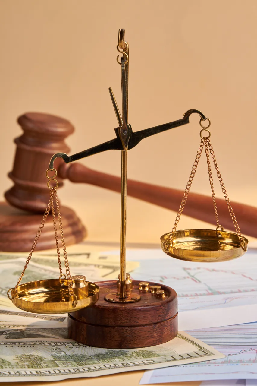 Balanza de justicia dorada sobre un fondo de documentos financieros y un mazo de juez, simbolizando la equidad en el sistema legal y la importancia de la justicia en asuntos económicos.